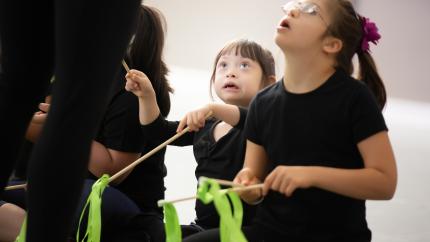 picture of little girls in black dresses waving green ribbons